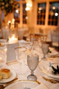 A candlelit table featuring Ace Party and Tent Rentals new blue goblet glassware and gold rim glassware featured at a wedding in New York.